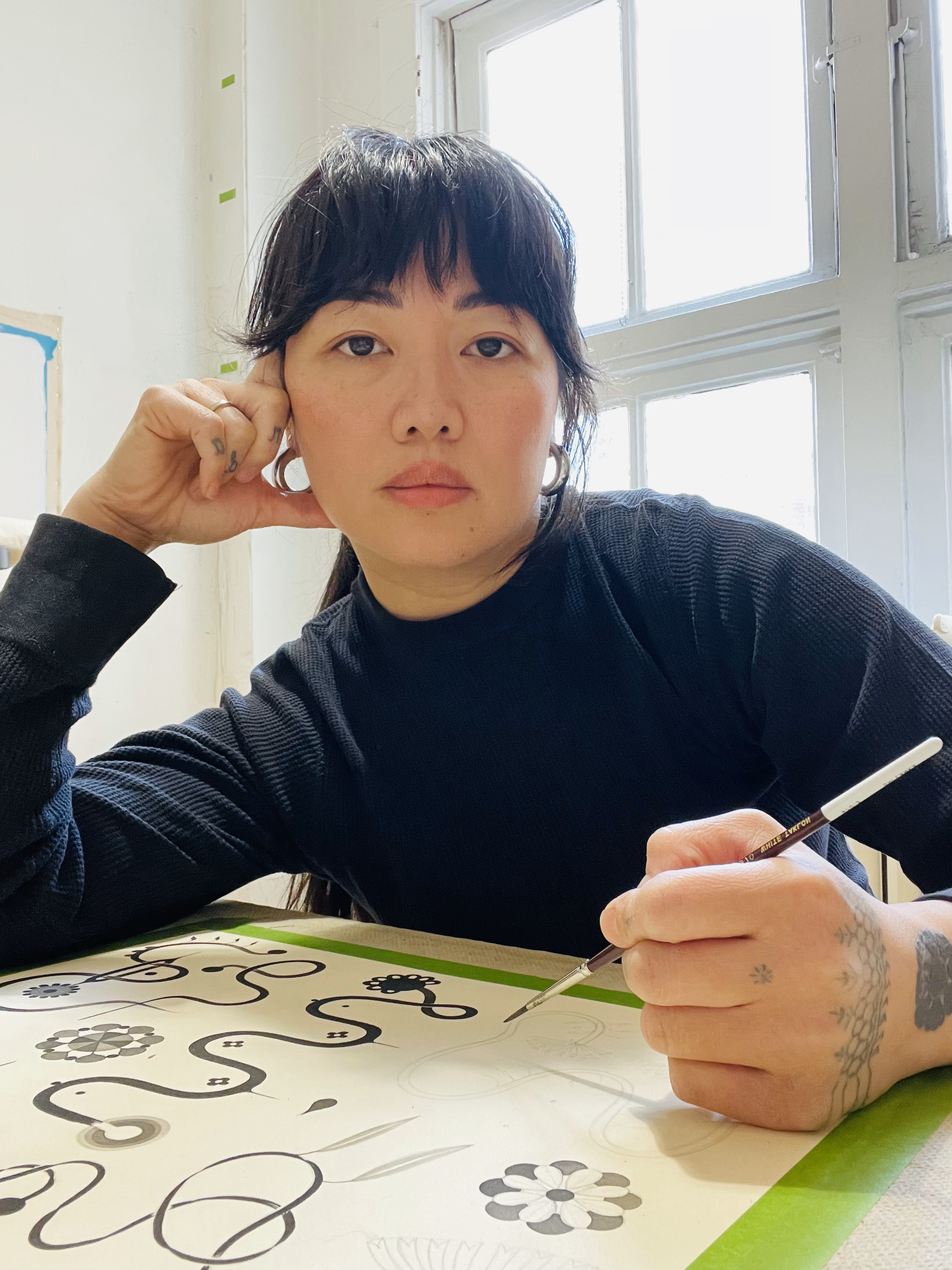 Photo of Marigold Santos sitting with a paintbrush in her hand