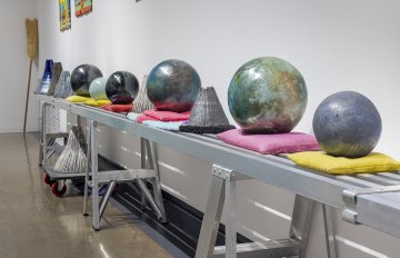 Side view of a metal table holding various ceramic globes