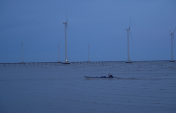 large wind tourbines on a lake with a person canoeing past them