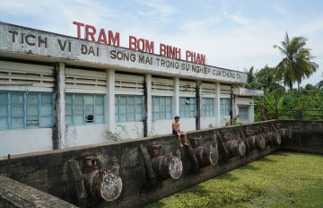 a boy sitting on top of a wall in front of a large abandoned building