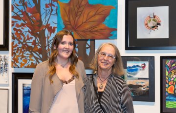 two girls standing in front of their artwork at the exhibition opening