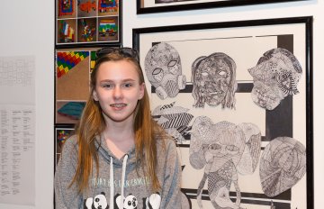 young girl standing in front of her artwork at the exhibition opening