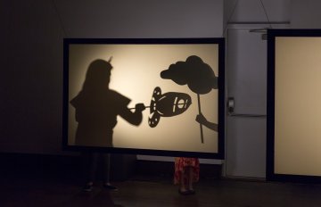 theatrical shadow performance showing a girl using puppets to create a story