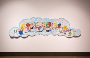 large artwork hung on wall that looks like clouds with different people inside it