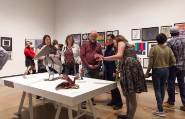 gallery shot of exhibition with people admiring the artwork