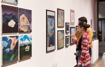 gallery shot of exhibition with people admiring the artwork