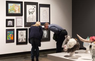 gallery shot of exhibition with people admiring the artwork