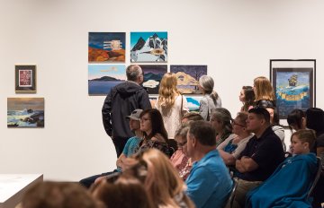 gallery shot of exhibition with people admiring the artwork