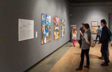people admiring the artwork on the wall of the exhibition