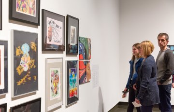 people admiring the artwork on the wall of the exhibition