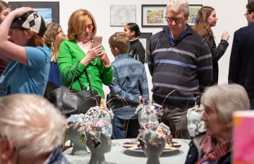 people admiring the sculptures on a display table in the gallery