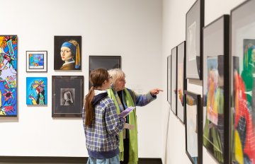 people admiring the artwork on the wall of the exhibition