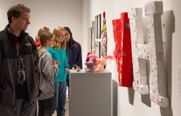 people admiring the artwork on the wall of the exhibition