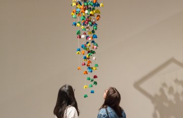 people admiring a sculpture hanging from the ceiling of the art gallery