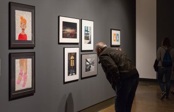 people admiring the artwork on the wall of the exhibition