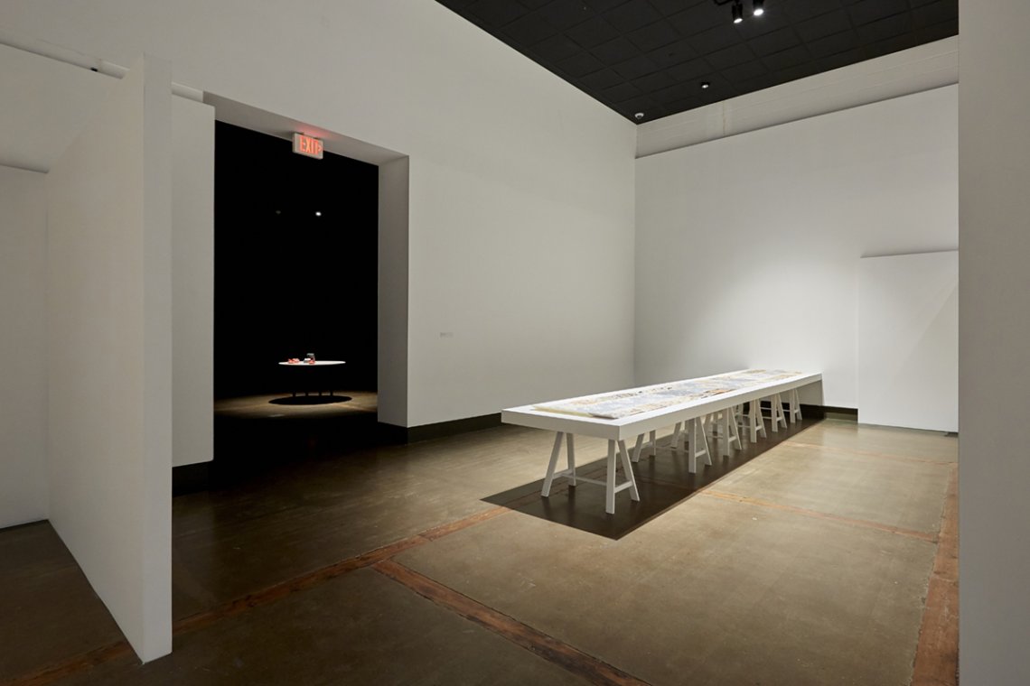 installation shot of exhibition with a long table in the middle