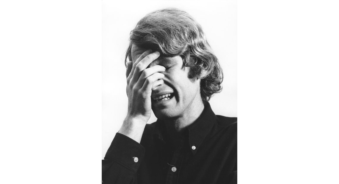Black and white photo of a person with hair covering their face with one hand, appearing to be crying.