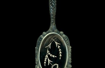 a green hand mirror with flowers painted on the glass