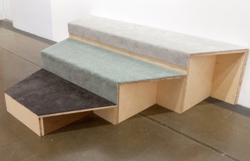 sculpture that looks like stairs in shades of grey pushed against a wall