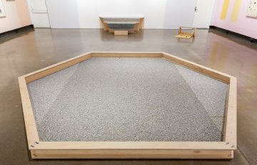 a grey hexagon made of wood with what looks like grey carpeting in the middle