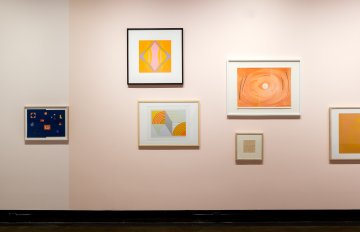 a pastel pink wall with pictures hung on it