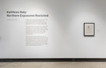 Didactic panel on white wall with a smaller framed artwork to the right.