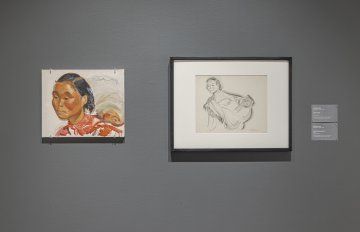 Grey wall with two artworks hung on them. A portrait of a woman of color on the left, with a conte sketch hung to the right of it.