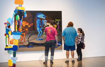 Photo of three people standing in front of a Lawrence Paul Yuxweluptun