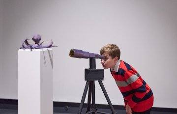 Young person looking through a papier mache scuplture of a periscope