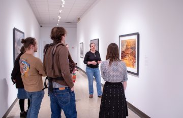 Group of people standing in the corridor gallery experiencing a tour with the KWAG registrar
