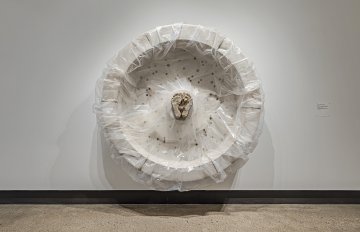 Concrete sculpture wrapped in plastic with a casting of feet emerging from the centre