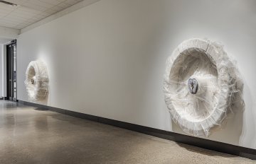 Concrete sculpture wrapped in plastic with a casting of feet emerging from the centre