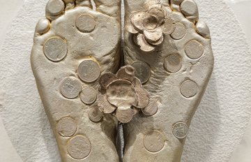 Concrete sculpture wrapped in plastic with a casting of feet emerging from the centre