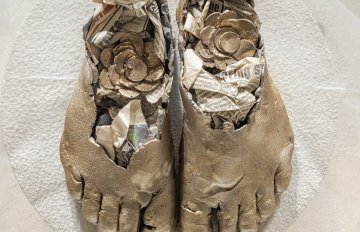 Concrete sculpture wrapped in plastic with a casting of feet emerging from the centre