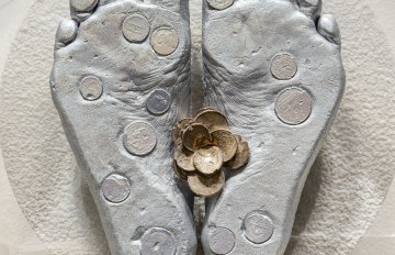 Concrete sculpture wrapped in plastic with a casting of feet emerging from the centre