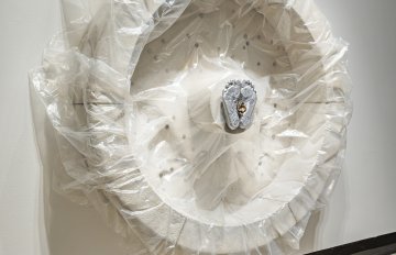 Concrete sculpture wrapped in plastic with a casting of feet emerging from the centre