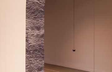 Installation view of imagery on the archway of the space with a sculpture in the background.