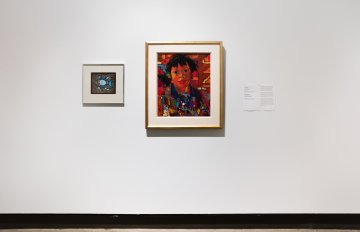 Two square, framed artworks hand on a white wall