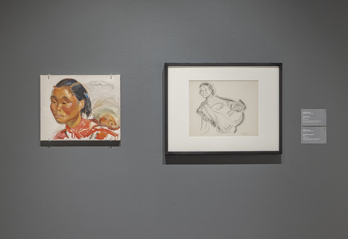Grey wall with two artworks hung on them. A portrait of a woman of color on the left, with a conte sketch hung to the right of it.