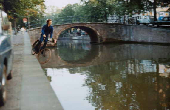 A video still from 16mm film of a man on a bicycle about to fall into a canal 